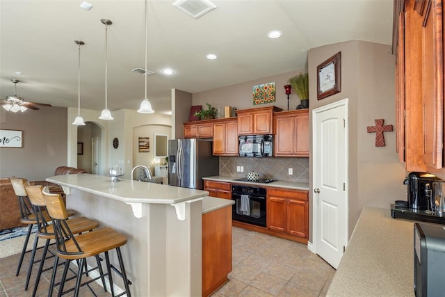 2308 SW 135th St, Oklahoma City, OK 73170 - kitchen with black appliances, arched walkways, brown cabinets, a kitchen breakfast bar, and a ceiling fan