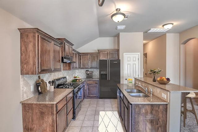 9544 SW 27th St, Oklahoma City, OK 73128 - kitchen featuring black range with gas cooktop, fridge with ice dispenser, under cabinet range hood, backsplash, and lofted ceiling
