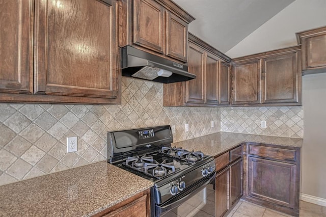 9544 SW 27th St, Oklahoma City, OK 73128 - kitchen with black gas range, under cabinet range hood, lofted ceiling, dark stone counters, and light tile patterned floors
