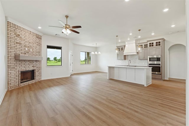 29744 Jade St, Cashion, OK 73016 - unfurnished living room with ceiling fan, recessed lighting, light wood-style flooring, a brick fireplace, and arched walkways