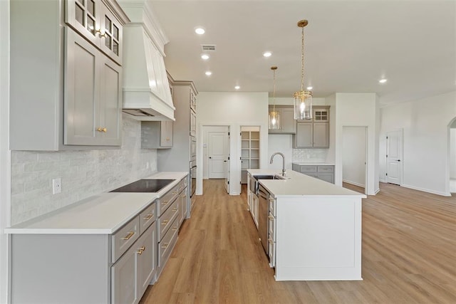 29744 Jade St, Cashion, OK 73016 - kitchen with custom range hood, black electric cooktop, gray cabinets, decorative backsplash, and light wood-style flooring