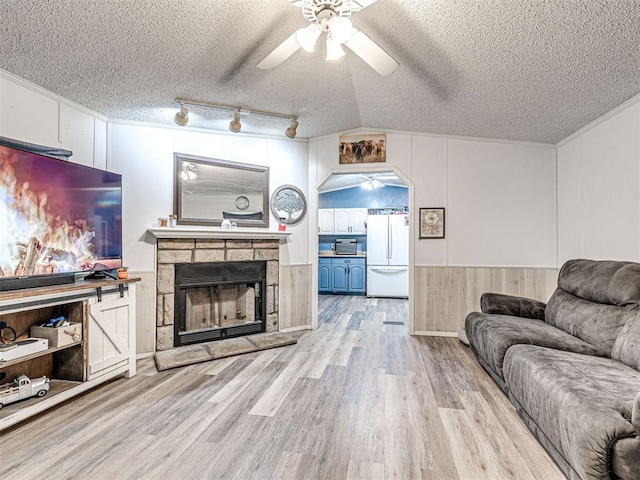 15251 E Waterloo Rd, Arcadia, OK 73007 - living area featuring ceiling fan, a textured ceiling, light wood-style floors, crown molding, and a stone fireplace