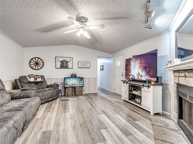 15251 E Waterloo Rd, Arcadia, OK 73007 - living room with a ceiling fan, light wood finished floors, vaulted ceiling, a textured ceiling, and a stone fireplace