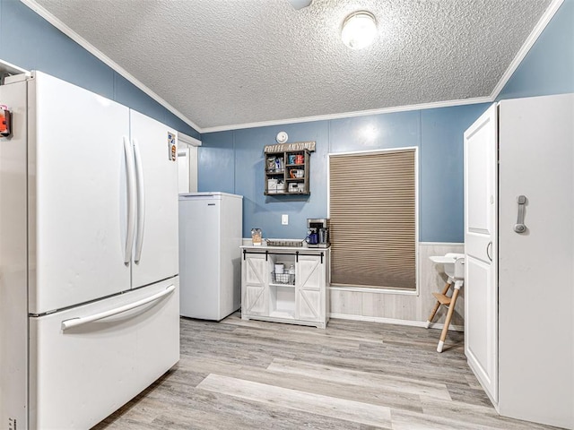 15251 E Waterloo Rd, Arcadia, OK 73007 - kitchen with freestanding refrigerator, ornamental molding, a textured ceiling, light wood finished floors, and refrigerator
