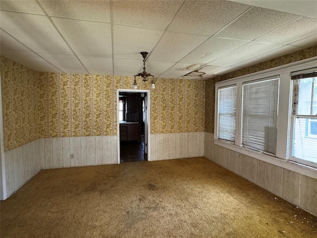 415 N Wentz St, Guthrie, OK 73044 - unfurnished dining area featuring a paneled ceiling, wainscoting, carpet flooring, wallpapered walls, and wooden walls