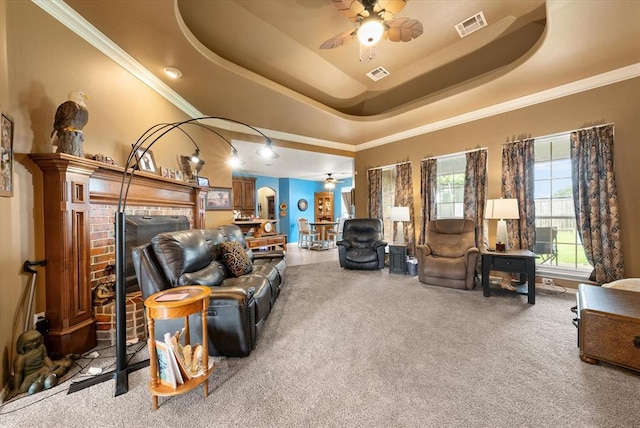 13117 SW 2nd Ter, Yukon, OK 73099 - carpeted living area featuring ceiling fan, a raised ceiling, a fireplace, and ornamental molding