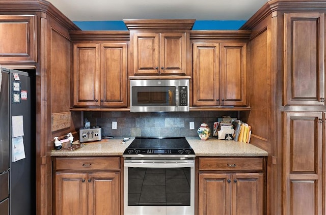 13117 SW 2nd Ter, Yukon, OK 73099 - kitchen with appliances with stainless steel finishes, light countertops, decorative backsplash, and brown cabinetry
