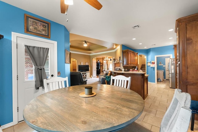13117 SW 2nd Ter, Yukon, OK 73099 - dining area featuring ceiling fan, arched walkways, light tile patterned floors, a tray ceiling, and ornamental molding