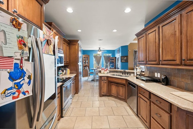 13117 SW 2nd Ter, Yukon, OK 73099 - kitchen featuring appliances with stainless steel finishes, a peninsula, brown cabinetry, recessed lighting, and light tile patterned flooring