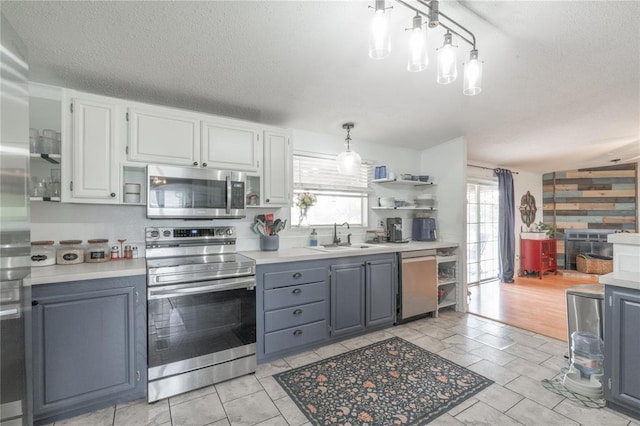 1300 Hutton Rd, Marlow, OK 73055 - kitchen featuring appliances with stainless steel finishes, open shelves, light countertops, gray cabinetry, and decorative light fixtures