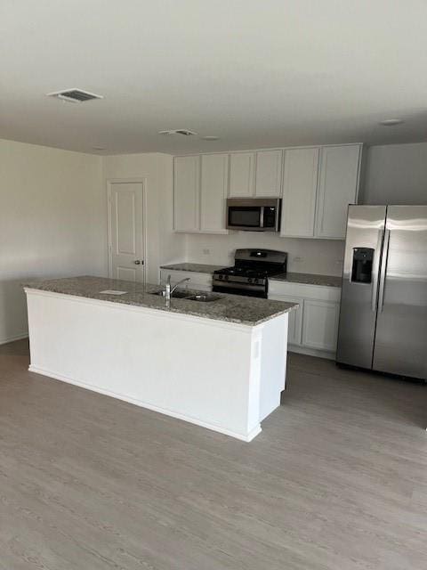 9616 NW 125th Ter, Yukon, OK 73099 - kitchen with appliances with stainless steel finishes, light wood-style flooring, dark stone countertops, and white cabinetry