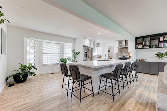 2401 Big Cedar Ave, Edmond, OK 73012 - kitchen featuring appliances with stainless steel finishes, light wood-type flooring, white cabinets, a breakfast bar area, and recessed lighting