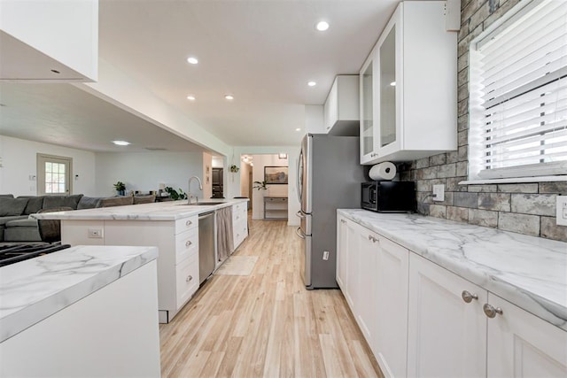 2401 Big Cedar Ave, Edmond, OK 73012 - kitchen with light wood-style floors, stainless steel appliances, open floor plan, light stone countertops, and white cabinetry