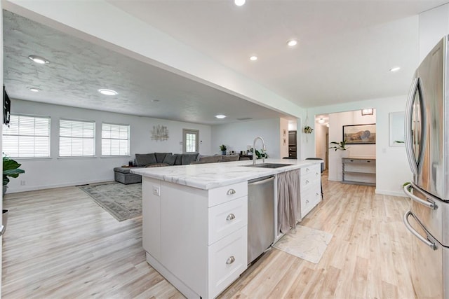 2401 Big Cedar Ave, Edmond, OK 73012 - kitchen featuring stainless steel appliances, a center island with sink, open floor plan, light stone counters, and white cabinetry