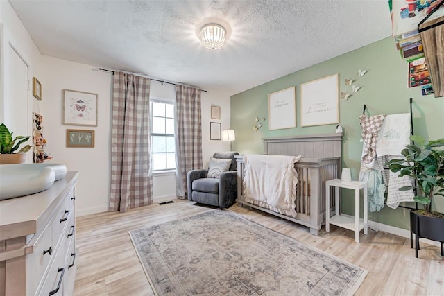 2401 Big Cedar Ave, Edmond, OK 73012 - bedroom with light wood-style flooring and a textured ceiling