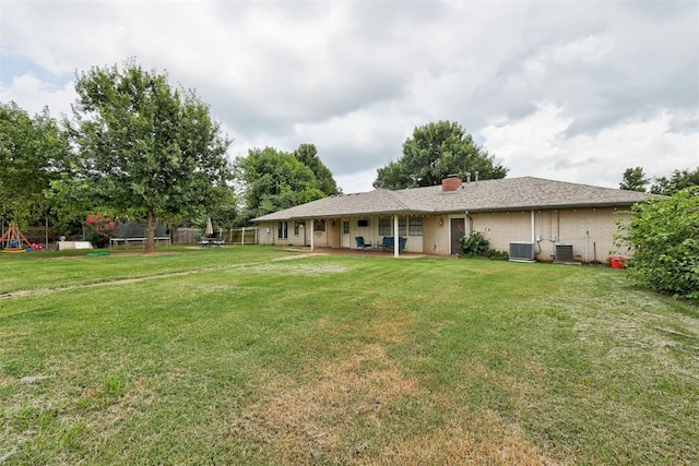 2401 Big Cedar Ave, Edmond, OK 73012 - back of property featuring a trampoline, a patio, a lawn, a chimney, and a playground