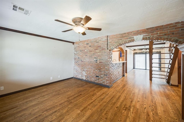 3824 Key Pl, Oklahoma City, OK 73112 - spare room with wood finished floors, arched walkways, ceiling fan, brick wall, and a chandelier
