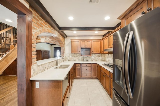 3824 Key Pl, Oklahoma City, OK 73112 - kitchen featuring stainless steel appliances, backsplash, under cabinet range hood, brown cabinetry, and beamed ceiling