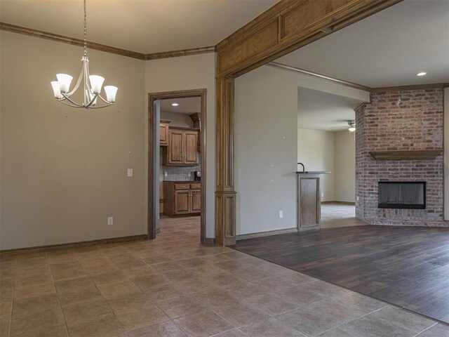 8409 NW 106th St, Oklahoma City, OK 73162 - unfurnished living room featuring crown molding, a chandelier, ceiling fan, a brick fireplace, and dark tile patterned flooring