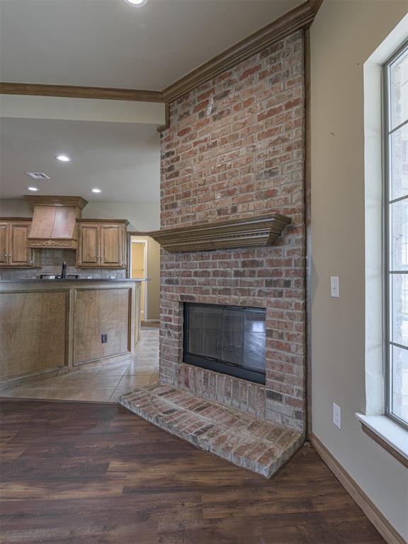 8409 NW 106th St, Oklahoma City, OK 73162 - unfurnished living room featuring light wood-type flooring, a fireplace, crown molding, plenty of natural light, and recessed lighting