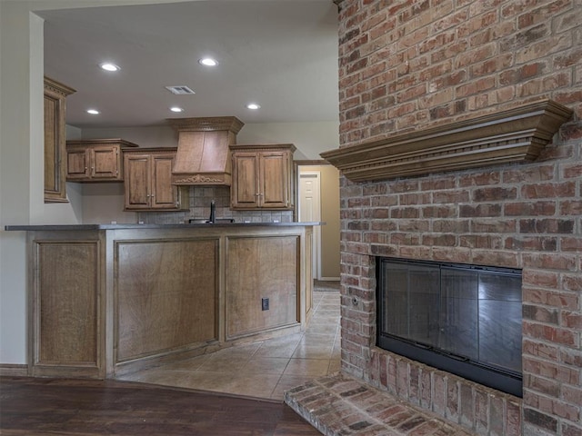 8409 NW 106th St, Oklahoma City, OK 73162 - kitchen featuring premium range hood, a fireplace, wood finished floors, brown cabinetry, and recessed lighting