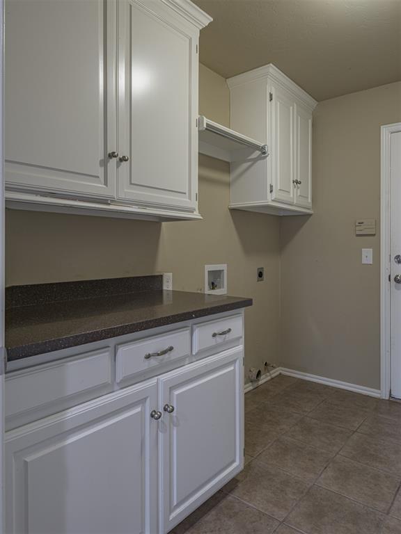 8409 NW 106th St, Oklahoma City, OK 73162 - laundry room featuring electric dryer hookup, cabinet space, dark tile patterned floors, and washer hookup