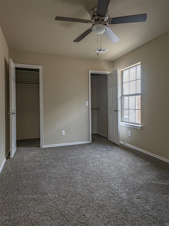 8409 NW 106th St, Oklahoma City, OK 73162 - unfurnished bedroom with carpet flooring, multiple closets, and a ceiling fan