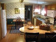 515 Logan Ave, Cashion, OK 73016 - kitchen with wallpapered walls, white appliances, brown cabinets, and wood finished floors