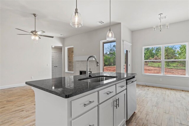 1244 Layla Ln, Blanchard, OK 73010 - kitchen featuring dishwasher, light wood-style floors, pendant lighting, a kitchen island with sink, and dark stone countertops