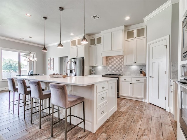 609 Newport Bridge Dr, Edmond, OK 73034 - kitchen with appliances with stainless steel finishes, crown molding, a chandelier, a center island with sink, and light countertops
