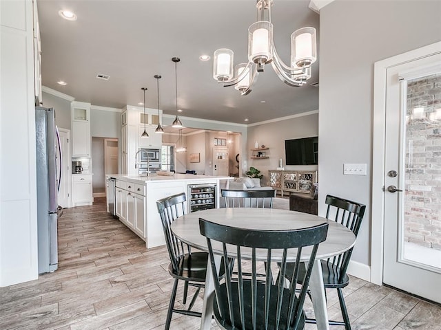 609 Newport Bridge Dr, Edmond, OK 73034 - dining space with crown molding, beverage cooler, light wood finished floors, a chandelier, and recessed lighting