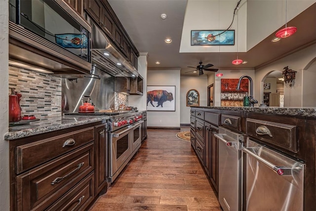 1701 Woodhill Rd, Edmond, OK 73025 - kitchen featuring range with two ovens, a ceiling fan, arched walkways, tasteful backsplash, and dark wood-style flooring