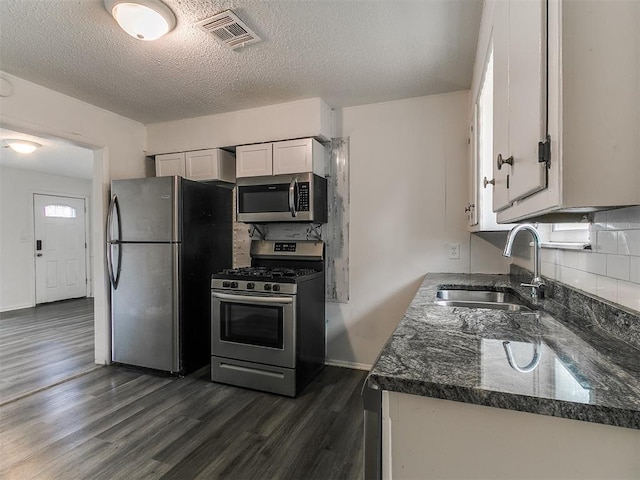650 NW 5th St, Moore, OK 73160 - kitchen with appliances with stainless steel finishes, dark wood-style flooring, decorative backsplash, white cabinetry, and a textured ceiling