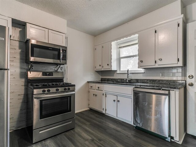 650 NW 5th St, Moore, OK 73160 - kitchen featuring stainless steel appliances, dark wood-style flooring, dark countertops, white cabinets, and a textured ceiling