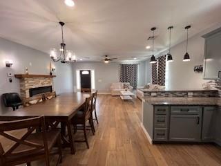 1727 NW 31st St, Oklahoma City, OK 73118 - dining area with a stone fireplace, wood finished floors, recessed lighting, ceiling fan, and a chandelier
