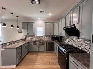 1727 NW 31st St, Oklahoma City, OK 73118 - kitchen with black range with gas cooktop, under cabinet range hood, gray cabinetry, a peninsula, and dark stone countertops