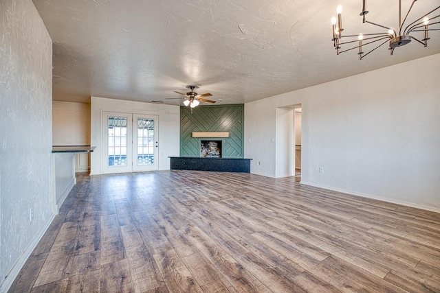 1212 S Main St, Kingfisher, OK 73750 - unfurnished living room with a chandelier, wood finished floors, ceiling fan, a textured ceiling, and a large fireplace