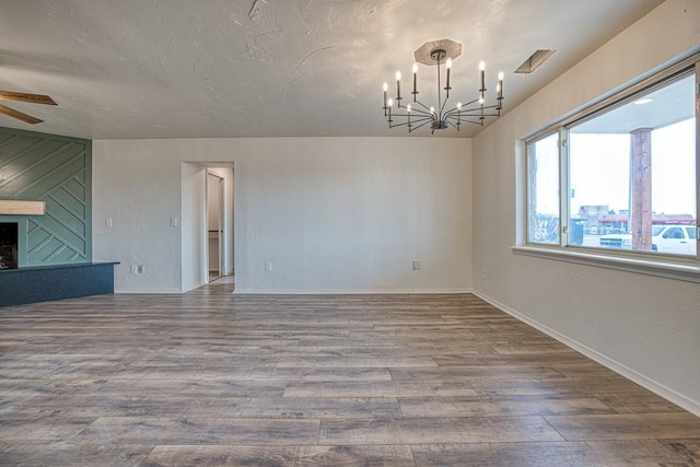 1212 S Main St, Kingfisher, OK 73750 - empty room featuring a chandelier, wood finished floors, a ceiling fan, and a fireplace