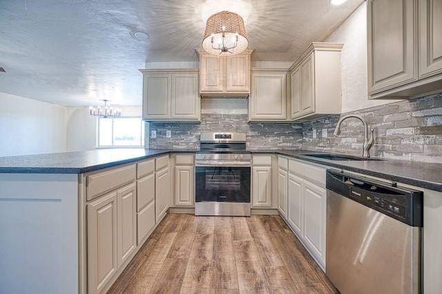 1212 S Main St, Kingfisher, OK 73750 - kitchen featuring appliances with stainless steel finishes, a chandelier, a peninsula, dark countertops, and light wood-style floors