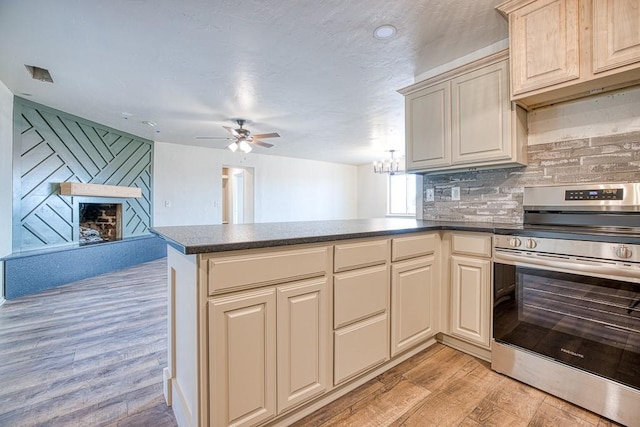 1212 S Main St, Kingfisher, OK 73750 - kitchen with stainless steel range with electric cooktop, a peninsula, light wood-type flooring, ceiling fan, and backsplash