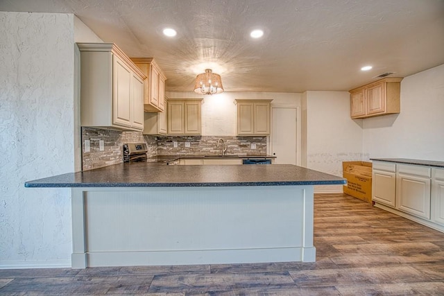 1212 S Main St, Kingfisher, OK 73750 - kitchen featuring stainless steel electric range oven, dark countertops, a textured wall, a peninsula, and backsplash