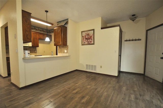 1333 SW 95th St, Oklahoma City, OK 73159 - kitchen featuring dark wood finished floors, light countertops, a textured ceiling, hanging light fixtures, and decorative backsplash