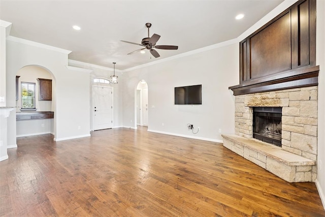 28 143rd St, Oklahoma City, OK 73170 - unfurnished living room featuring ceiling fan, arched walkways, ornamental molding, a stone fireplace, and wood finished floors