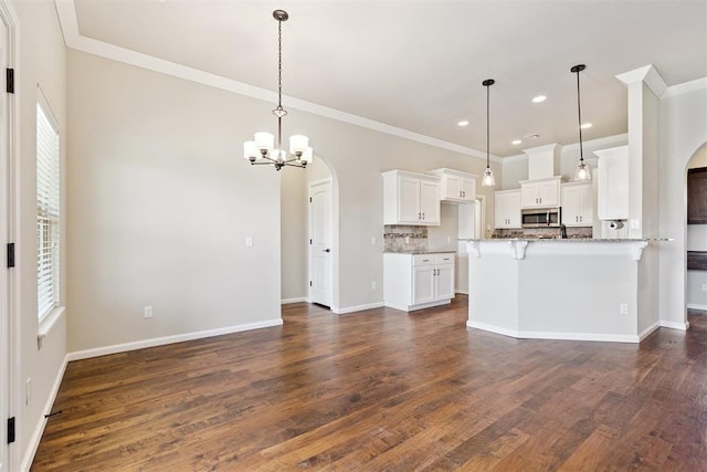 28 143rd St, Oklahoma City, OK 73170 - kitchen with stainless steel microwave, arched walkways, ornamental molding, a chandelier, and white cabinetry