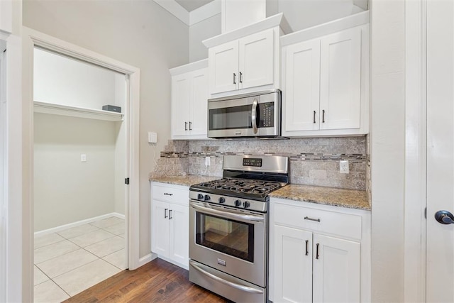 28 143rd St, Oklahoma City, OK 73170 - kitchen with stainless steel appliances, tasteful backsplash, light stone counters, and white cabinetry