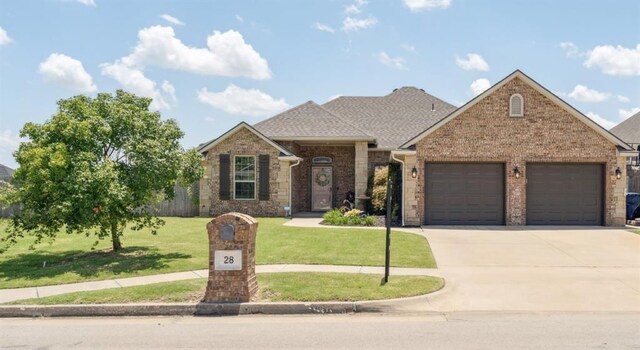 28 143rd St, Oklahoma City, OK 73170 - view of front of home featuring a garage, driveway, a front yard, brick siding, and roof with shingles