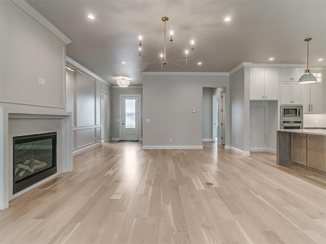 6104 NW 147th Ter, Oklahoma City, OK 73142 - unfurnished living room featuring crown molding, recessed lighting, light wood-style floors, a glass covered fireplace, and a chandelier