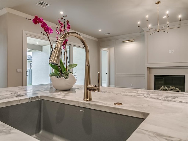 6104 NW 147th Ter, Oklahoma City, OK 73142 - kitchen with light stone countertops, a chandelier, a glass covered fireplace, and recessed lighting