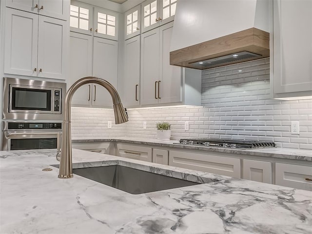 6104 NW 147th Ter, Oklahoma City, OK 73142 - kitchen featuring premium range hood, stainless steel appliances, white cabinetry, and decorative backsplash