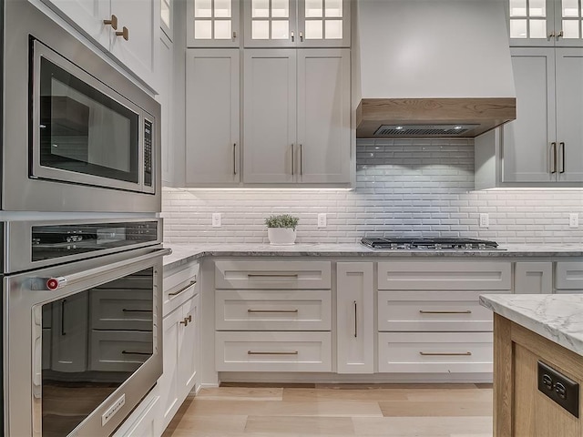 6104 NW 147th Ter, Oklahoma City, OK 73142 - kitchen featuring custom exhaust hood, appliances with stainless steel finishes, light stone countertops, and decorative backsplash